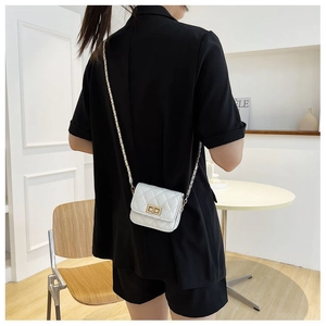 Macro di una mini borsa a tracolla bianca trapuntata con catena dorata su una modella