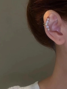 Close-up of elegant gold ear cuff with alternating pearls and sparkling zircons