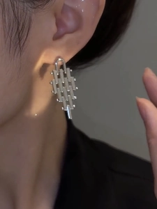 Detail view of silver geometric fringe earrings showing metallic texture on a model