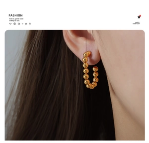 Detailed macro shot of 18k gold-plated beaded U-shaped earrings on a model's ear