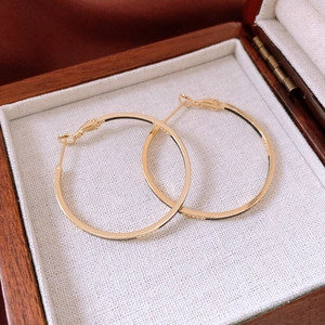Close-up of 14k gold plated round hoop earrings with snap closure on linen background