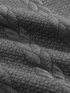 Macro view of dark grey heavy jacquard fabric with honeycomb texture and quilting