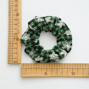 Christmas green plaid scrunchie with white snowflake patterns on a white background