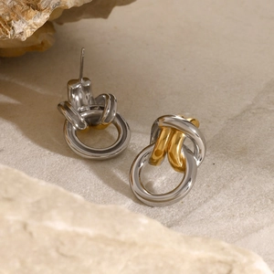 Détail macro de boucles d'oreilles nœuds bicolores en finition or et argent poli
