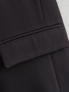 Detailed macro shot of the pocket flap and fine fabric texture on a black blazer