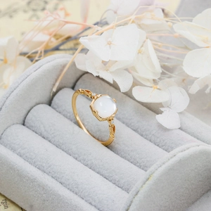 Macro detail of gold vintage ring with moonstone and floral engraving in a gray box