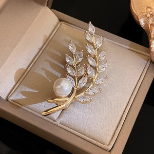 Macro detail of wheat ear brooch with gold plating, marquise cubic zirconia and large pearl