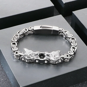 Detailed close-up of double wolf head clasp on silver Byzantine chain men's bracelet