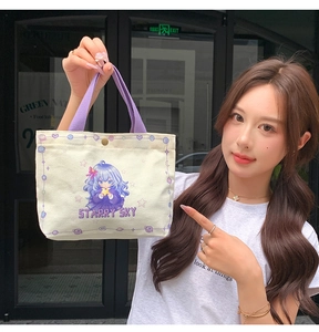Detail of compact canvas handbag with purple handle and starry sky cartoon illustration