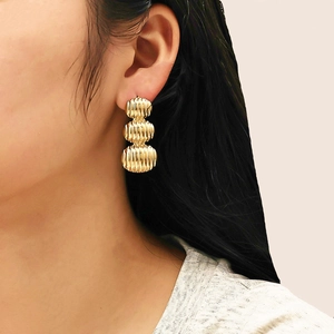 Gros plan de boucles d'oreilles ovales triples dorées avec rayures verticales élégantes
