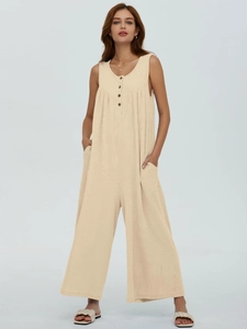Detail of ribbed beige sleeveless jumpsuit showing button closure and side pockets