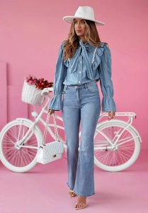 Détail d'un chemisier bleu clair à volants avec un jean denim évasé pour l'été