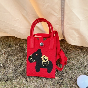 Detail of red knitted mini phone bag featuring a cartoon horse design on green grass