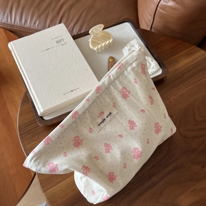 Floral print cotton makeup bag in cream with pink flowers on a wooden desk setting