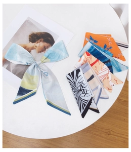 Detailed view of various colorful printed silk scarves neatly arranged on a white table