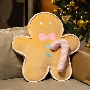 Close-up of plush gingerbread man pillow with candy cane on a sofa by a Christmas tree