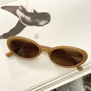 Retro oval translucent tea sunglasses with minimalist pin detail on fashion magazine
