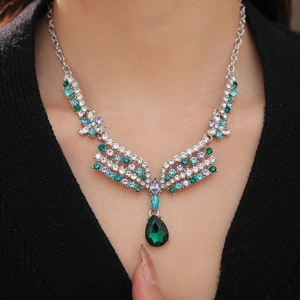 Detail of vintage silver necklace with colorful rhinestones and emerald drop gemstone