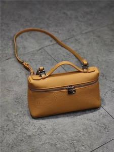 Detail view of yellow lychee grain leather handbag with silver zipper and metal hardware
