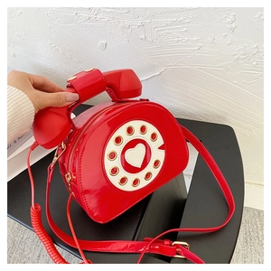 Detail of red telephone shaped patent leather crossbody bag with heart dial design