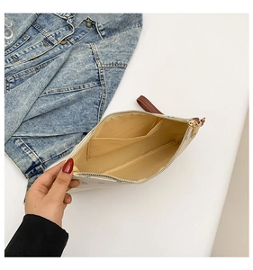 Interior view of beige straw clutch bag with fabric lining, main compartment and wrist strap