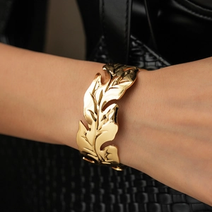 Detailed view of wide golden leaf cuff bracelet with realistic metal leaf texture