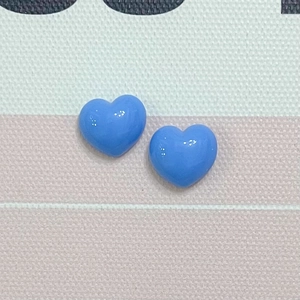 Macro shot of two blue glossy resin heart charms placed on a pink striped mat