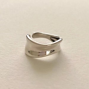 Close-up of minimalist wavy silver ring with polished finish and open adjustable band