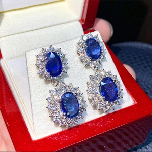 Eleganti orecchini pendenti con zaffiro blu e cristalli in una scatola di velluto rosso