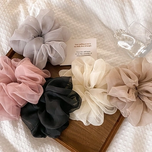 Detail of five pastel mesh scrunchies in gray, pink, black, cream, and khaki on a tray