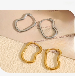Macro shot of minimalist polished wavy gold and silver stainless steel earrings