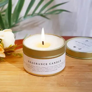 Minimalist golden tin scented candle with white wax on a wooden tray with greenery