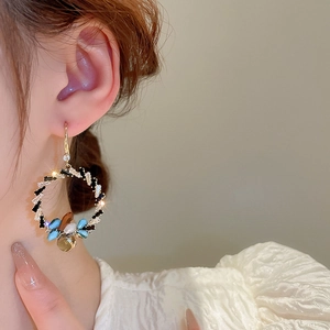 Elegant gold hoop earrings with colorful crystals worn by a model in close-up shot