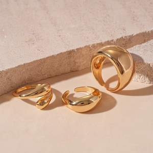 Detailed shot of three chunky gold polished geometric rings on a stone surface