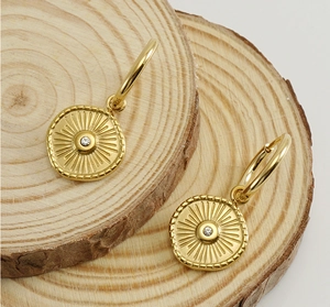 Detail of 18K gold plated hoop earrings with sunburst pendant and crystal inlay
