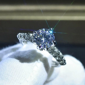 Dettaglio macro di un anello con diamante a sei griffe e taglio rotondo con pavé in argento