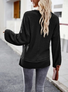 Back view of black waffle knit long sleeve top showing detailed fabric texture and loose fit