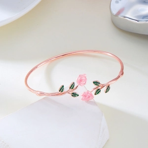 Detail of rose gold open cuff bracelet with pink enamel flowers and green leaves