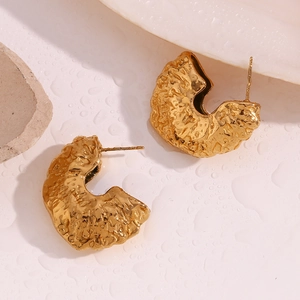 Macro shot of 18K gold plated fan-shaped earrings with hammered texture and water drops