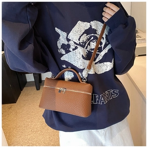 Close-up of brown lychee texture leather handbag with top handle and crossbody strap