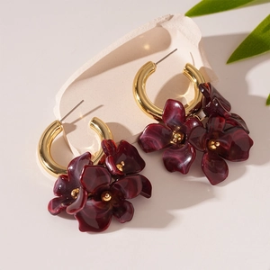 Gros plan de boucles d'oreilles fleurs en acrylique rouge foncé avec anneaux dorés