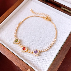 Detail eines 18k Gold-Herzarmbands mit bunten Edelsteinen und glänzenden Zirkonen