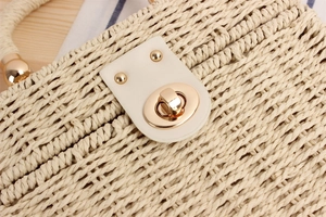 Detailed macro view of woven beige straw bag with premium gold metal twist lock