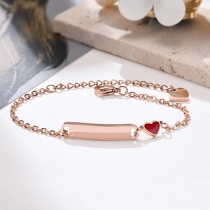 Détail du bracelet d'identité en acier doré rose avec pendentif coeur rouge