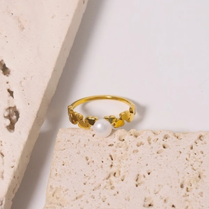 Bague élégante en or avec cœurs et perle blanche sur pierres décoratives, style minimaliste