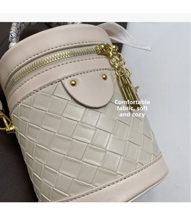 Detail view of woven leather bucket bag with silk scarf handle and gold hardware