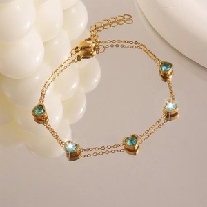 Dettaglio del bracciale a doppio strato a cuore dorato con cinque zirconi blu su base a specchio