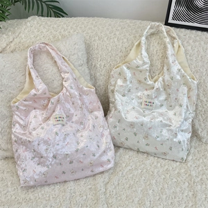 Detail view of pink and white floral teddy bear print satin tote bags with brand label