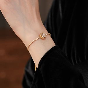 Close-up of golden clover rotating bracelet with zircons on model wrist