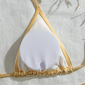 Detail view of gold bikini top showing white inner lining and removable round chest pads